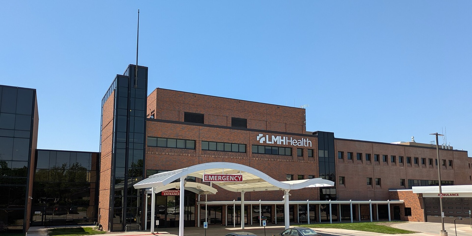 Brick hospital building with a white canopy over the emergency entrance and an ambulance bay sign